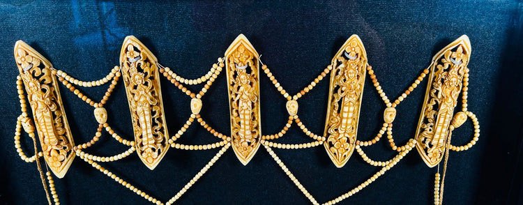 19th-century Tibetan Tantric ritual bone apron (rus gyan) displayed in black frame, featuring six carved bone plaques depicting Chakrasamvara deities, intricate bead lattice, cotton backing, and natural pigments — sacred Himalayan Buddhist ceremonial garment.