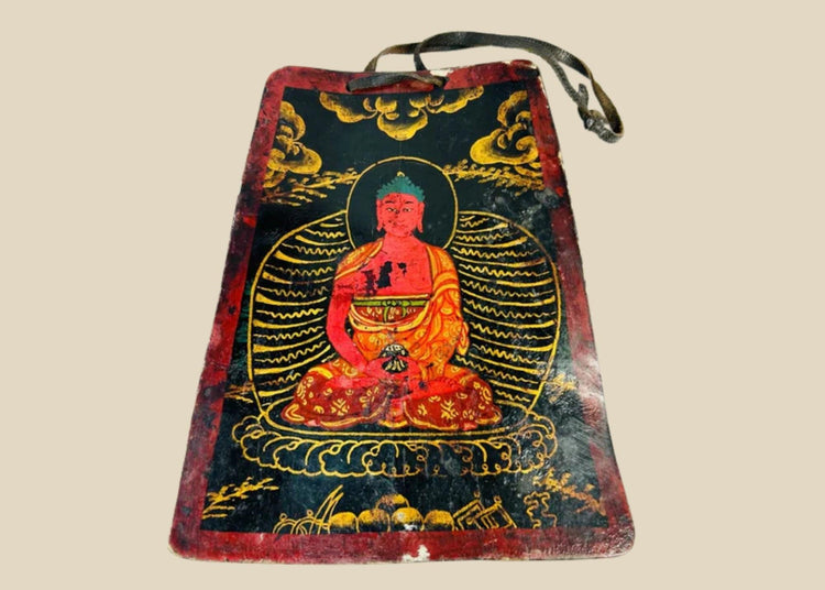 Late Qing Dynasty Tibetan devotional plaque, circa 19th century, hand-painted with vivid polychrome depiction of a seated Buddha in red and gold robes, surrounded by radiant aureole and cloud motifs; crafted on a rectangular wooden panel with suspension cord, showing surface wear and patina from ritual use.