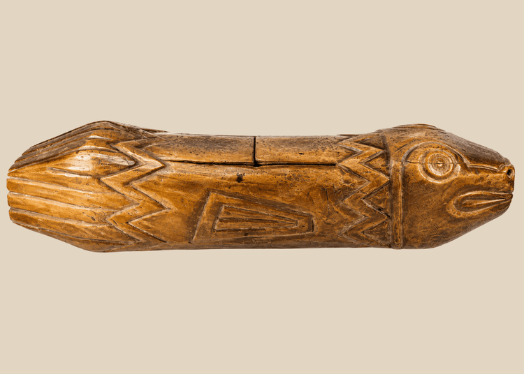Full side view of hand-carved Melanesian wooden fish drum showing detailed incised patterns