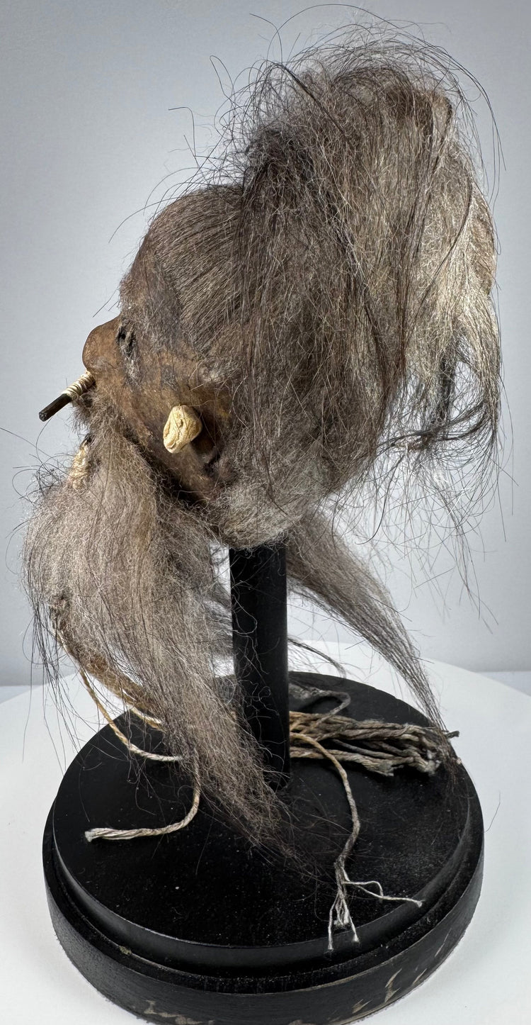 Mid-century ethnographic curiosity modeled after a Jivaroan tsantsa, with sewn facial details and natural horse hair.