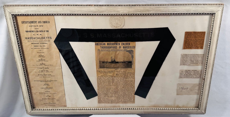 Museum-style presentation of USS Massachusetts naval artifacts including a 1910 entertainment program
