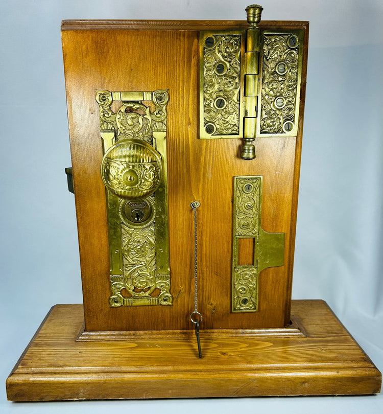 Vintage brass door hardware display with ornate doorknob and hinge assembly