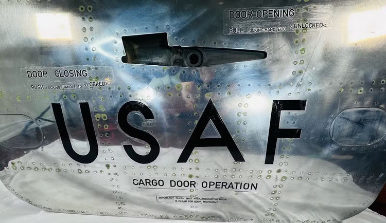Lower section of the aircraft cargo door with bold USAF lettering, rivets and cargo door operation stencil