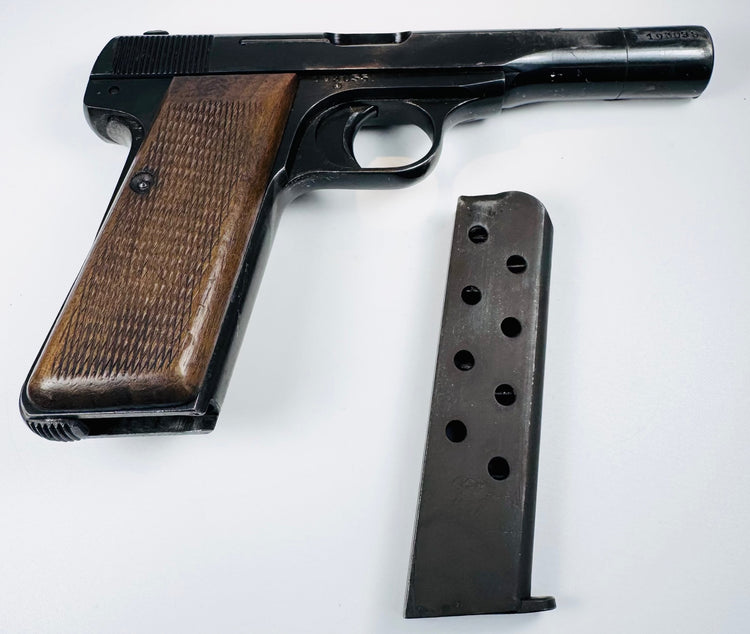 FN Browning Model 1922 with a detached magazine alongside its sloping walnut grip, long slide, and curved trigger guard.