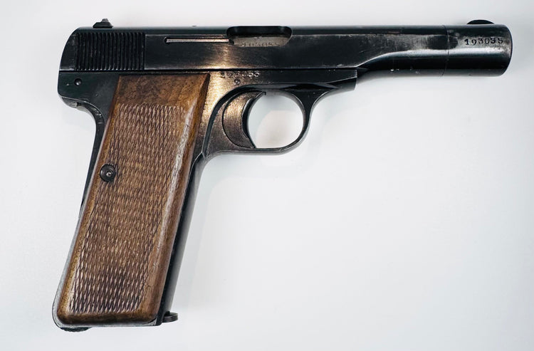 Belgian FN Browning Model 1922 with a visible ejection port, worn blued finish, and finely checkered wooden grip.