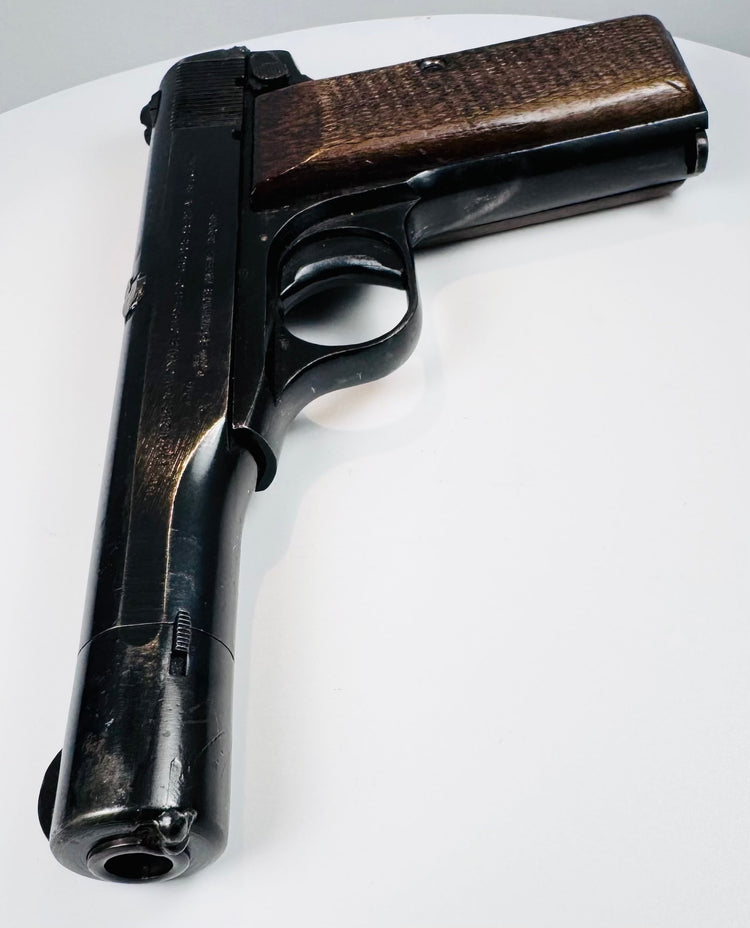 FN Browning Model 1922 highlighting the barrel opening, elongated steel slide, curved trigger guard, and checkered walnut grip.
