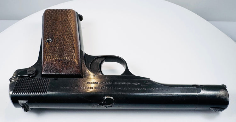 FN Browning Model 1922 resting on a white surface, showing the narrow slide, rounded barrel contours, and walnut grip base.