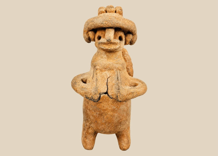 Pre-Columbian West Mexican terracotta standing effigy, likely Jalisco/Nayarit, circa 100 BCE–300 CE, hand-modeled with turban-style headdress, large earspools, hands-to-chest pose, and circular perforated back disk interpreted as warrior shield, mounted on modern display base, mineral accretions and ancient wear visible