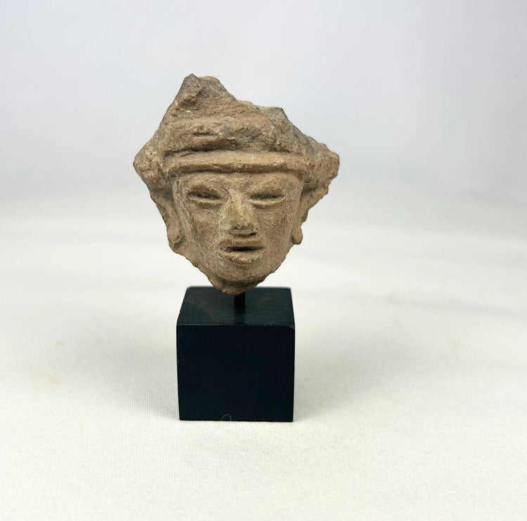 Fragmentary hand-modeled terracotta head of a male figure with almond-shaped eyes, parted lips, raised headband, and stylized coiffure; Western Mexico (Nayarit, Jalisco, or Colima), Late Formative to Early Classic period, circa 200 BCE–300 CE; mounted on custom display stand.