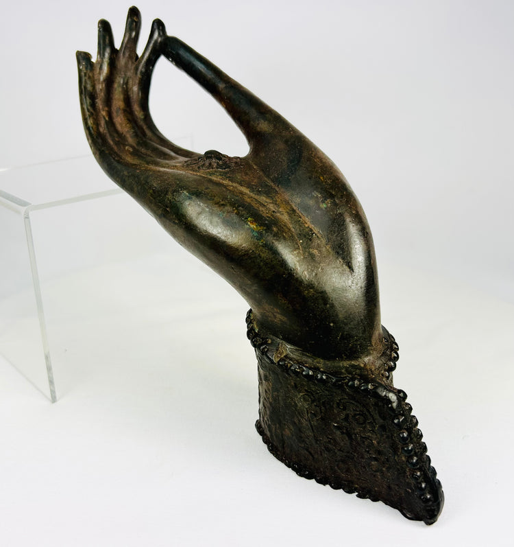 Bronze Buddha hand fragment from 18th–19th century Northern Thailand or Laos with elongated fingers, palm rosette/chakra, original wrist cuff with beaded edge, rich brown-olive patina, traces of lacquer and earthen accretions, representing Abhaya or Vitarka mudrā in Lanna/Lan Xang Buddhist art.