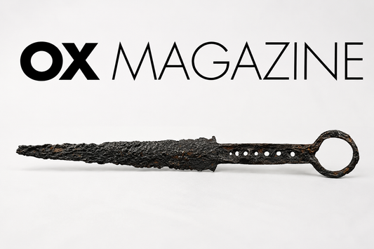 Ancient corroded iron dagger displayed beneath the OX Magazine logo on a minimalist editorial-style background, representing historical dagger collecting, rarity, and antique weapon authenticity.