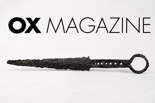 Ancient corroded iron dagger displayed beneath the OX Magazine logo on a minimalist editorial-style background, representing historical dagger collecting, rarity, and antique weapon authenticity.