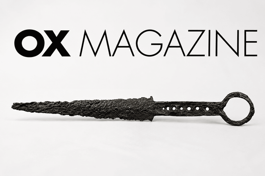 Ancient corroded iron dagger displayed beneath the OX Magazine logo on a minimalist editorial-style background, representing historical dagger collecting, rarity, and antique weapon authenticity.