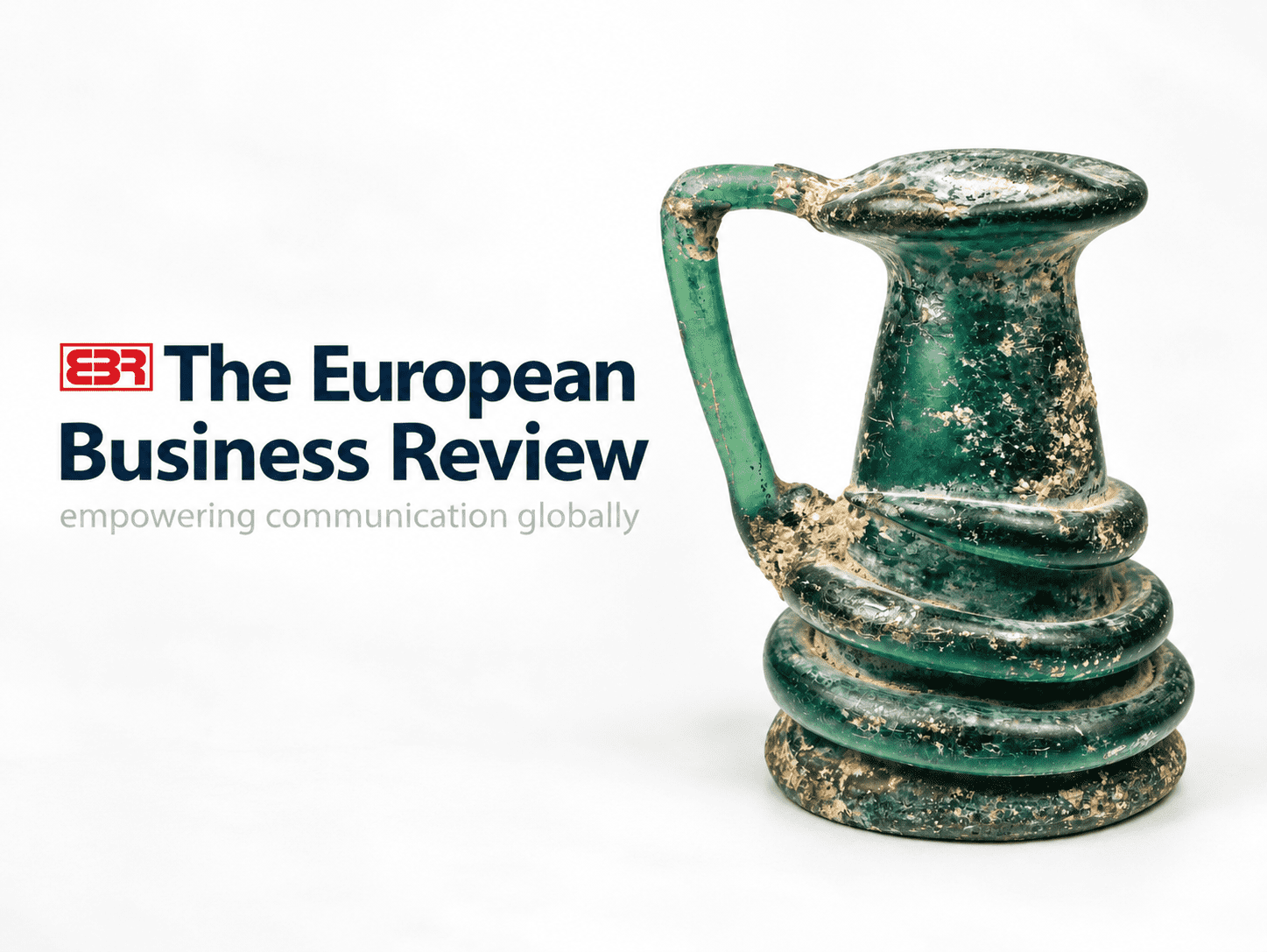 Relic & Rarity featured in The European Business Review, alongside an ancient Roman green glass vessel with a curved handle, applied spiral decoration, and naturally aged patina.