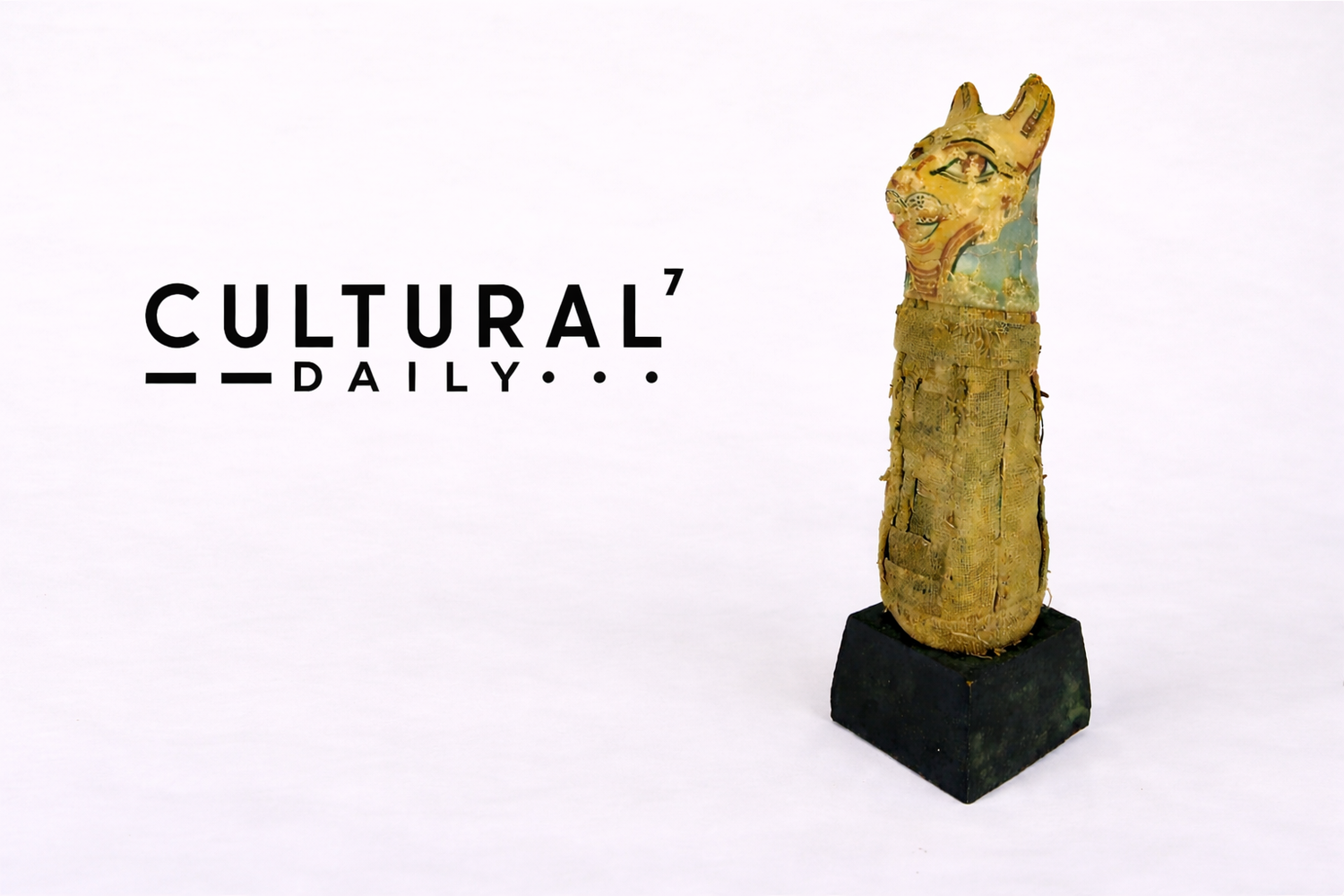 Cultural Daily publication logo displayed beside an ancient Egyptian Bastet votive cat mummy with linen wrappings mounted on a display base against a neutral studio background.