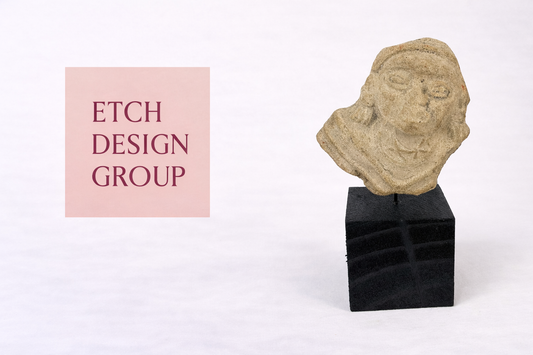 Etch Design Group interior design studio logo displayed beside an ancient carved stone head artifact from the Relic & Rarity collection.