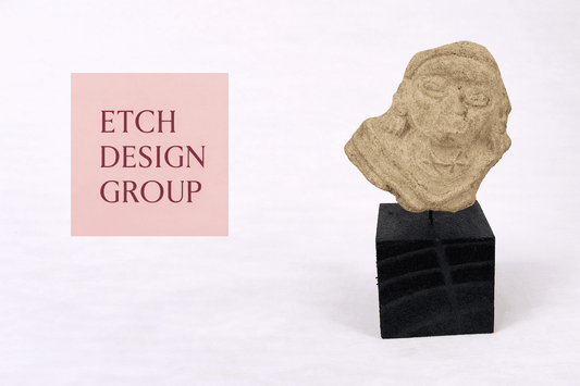 Etch Design Group interior design studio logo displayed beside an ancient carved stone head artifact from the Relic & Rarity collection.