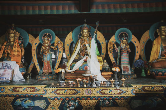 Traditional Tibetan Buddhist shrine featuring ornate deity statues, ritual offerings, and sacred Himalayan artwork