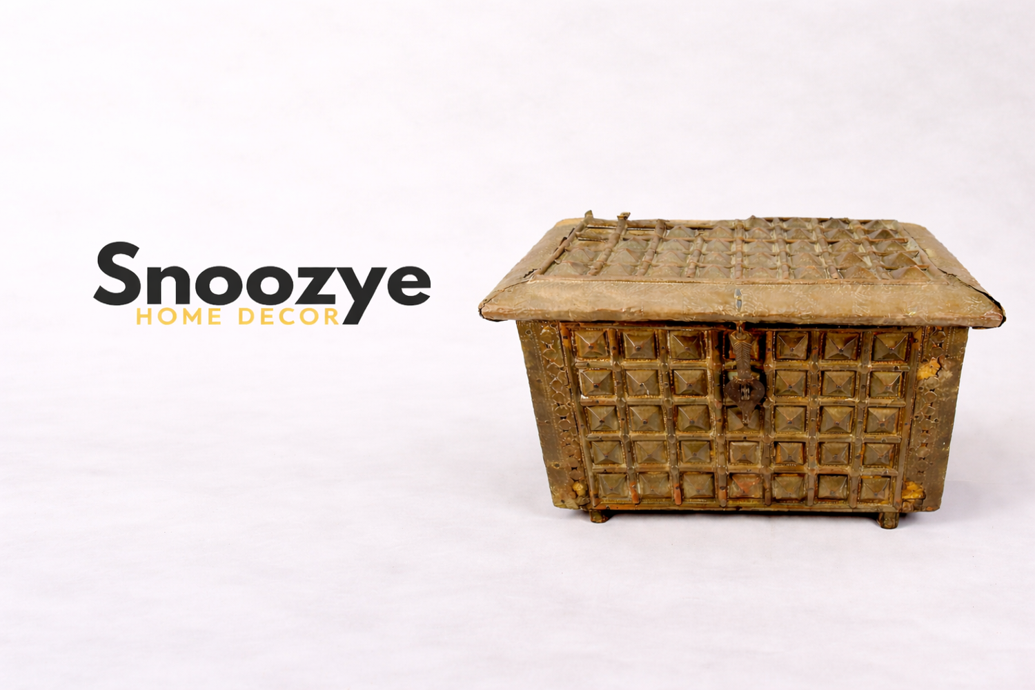 Snoozye Home Decor logo displayed beside an antique studded metal chest artifact from the Relic & Rarity collection.