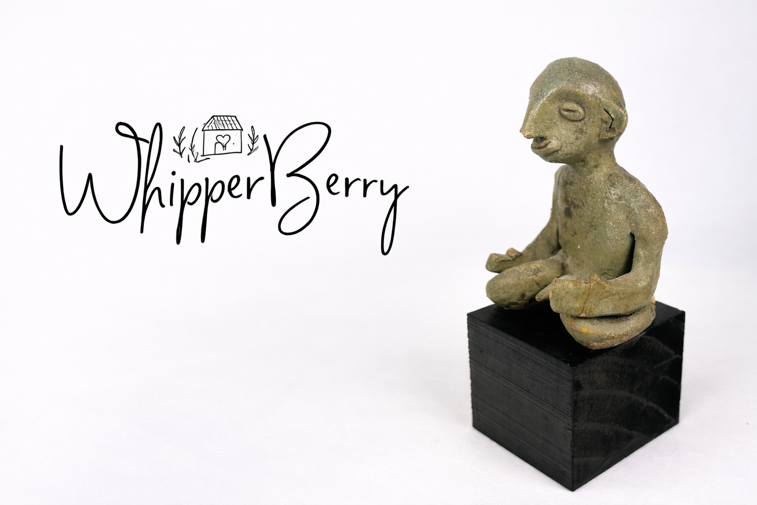 WhipperBerry blog logo displayed beside a small ancient terracotta seated figurine mounted on a black pedestal against a neutral studio background.