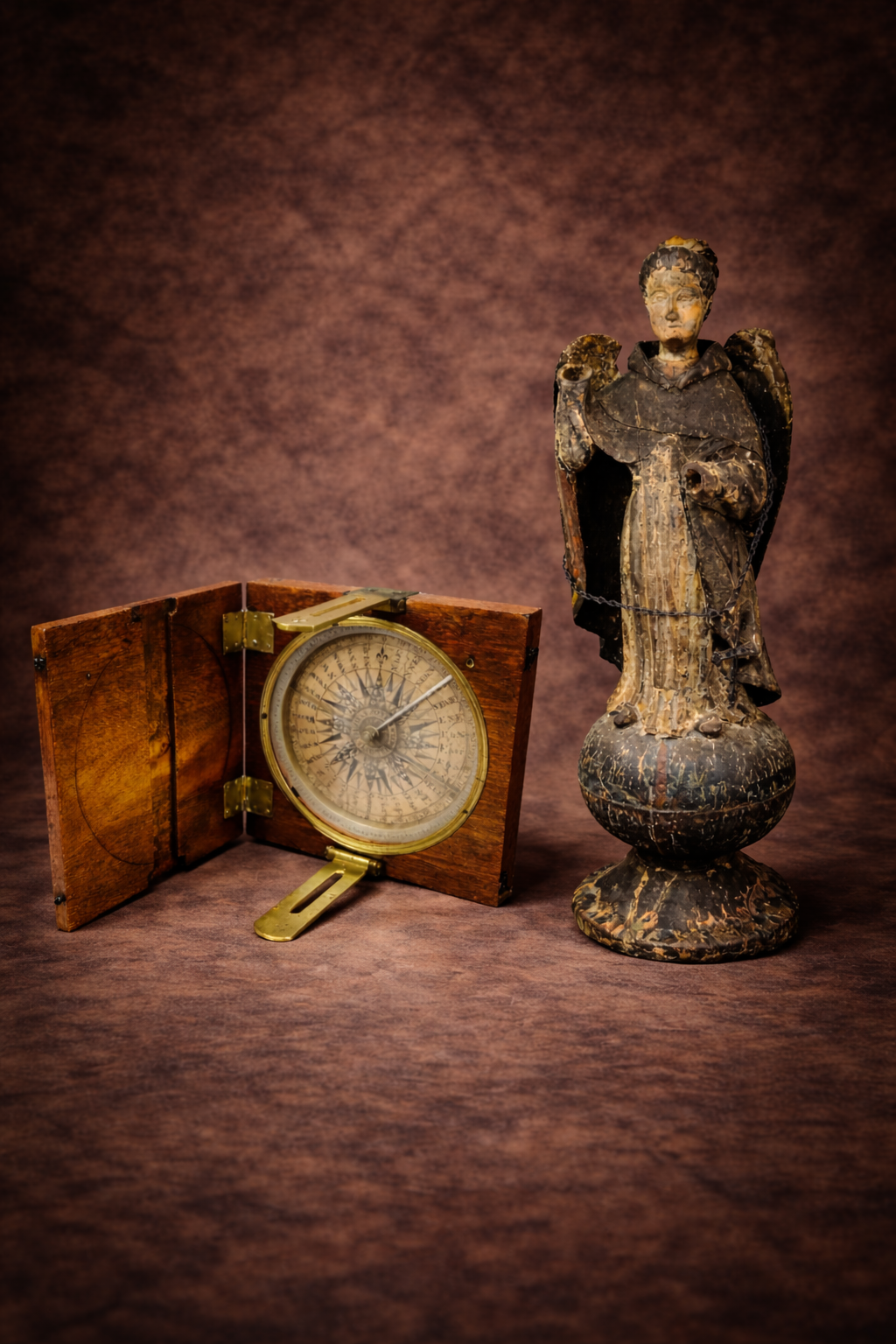 Mid-19th century alidade compass in walnut case displayed beside a Spanish Colonial polychrome wooden angel statue against a studio backdrop.