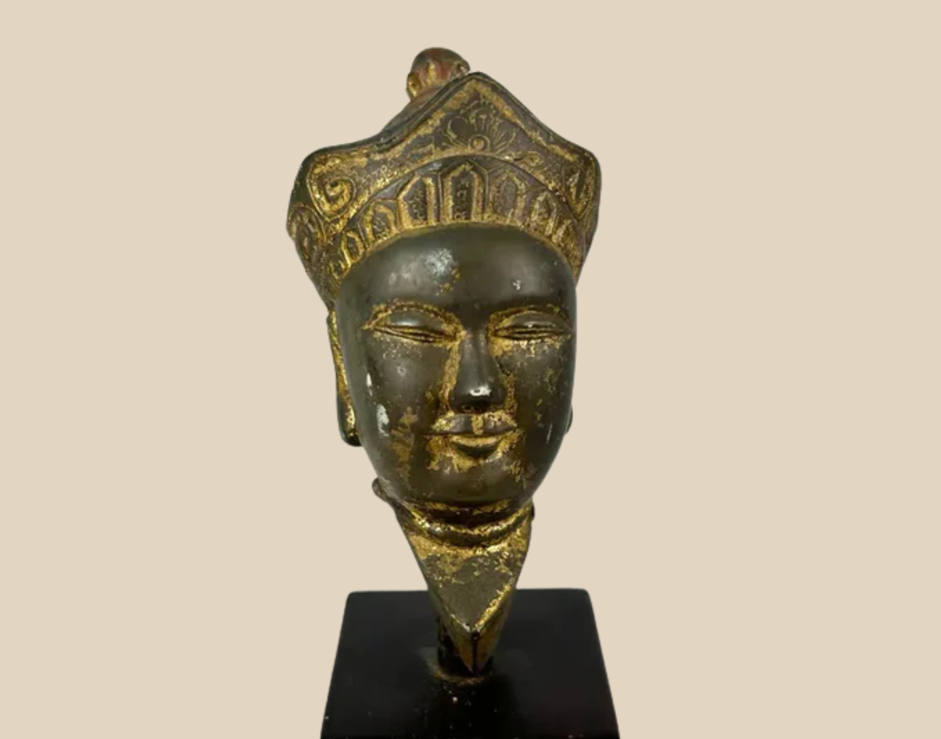 Bronze Buddha head with ornate crown, mounted on a black display base – a finely detailed Buddhist devotional artifact.
