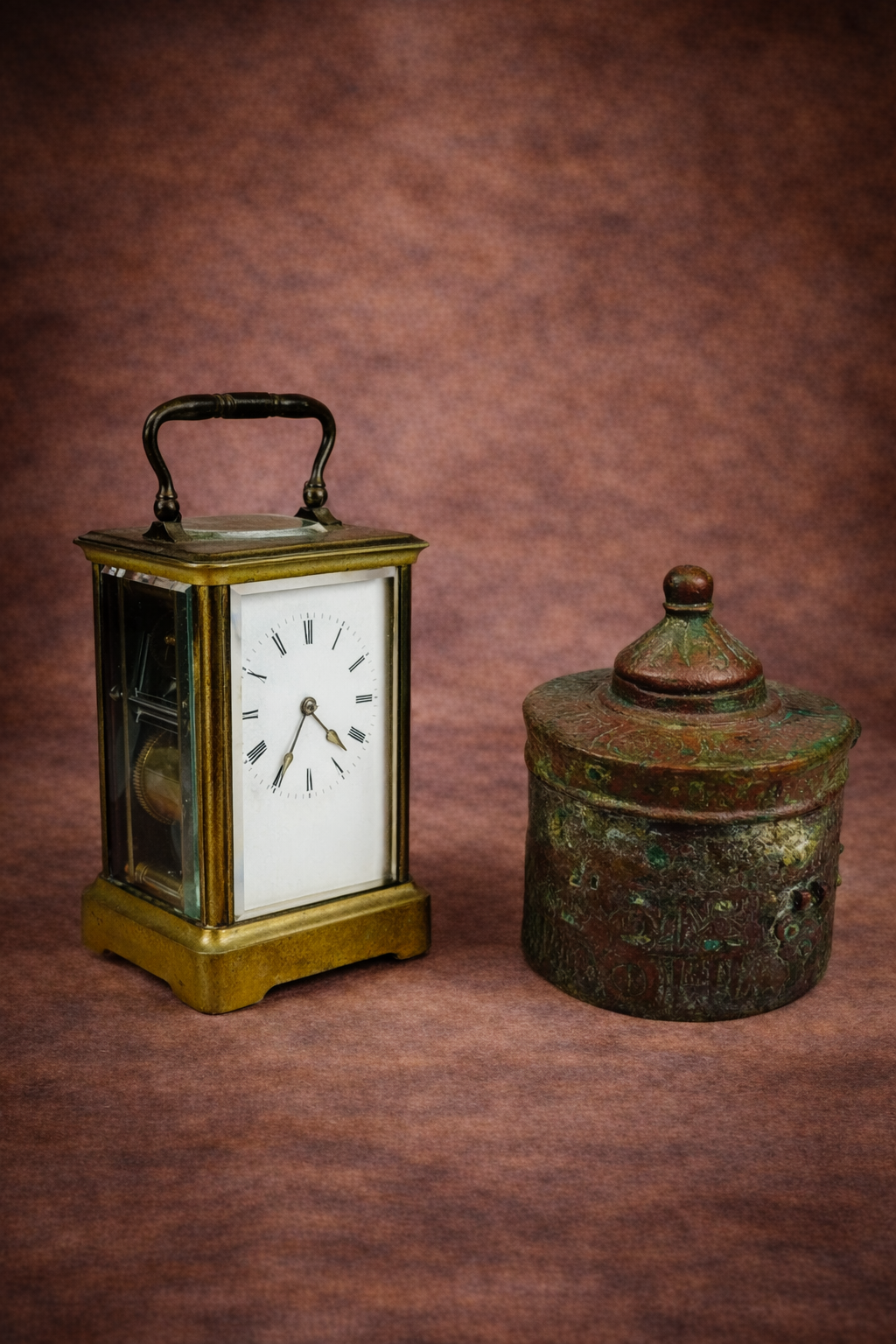 Antique French brass carriage clock displayed beside an engraved Khorassan bronze inkwell against a warm brown studio background.
