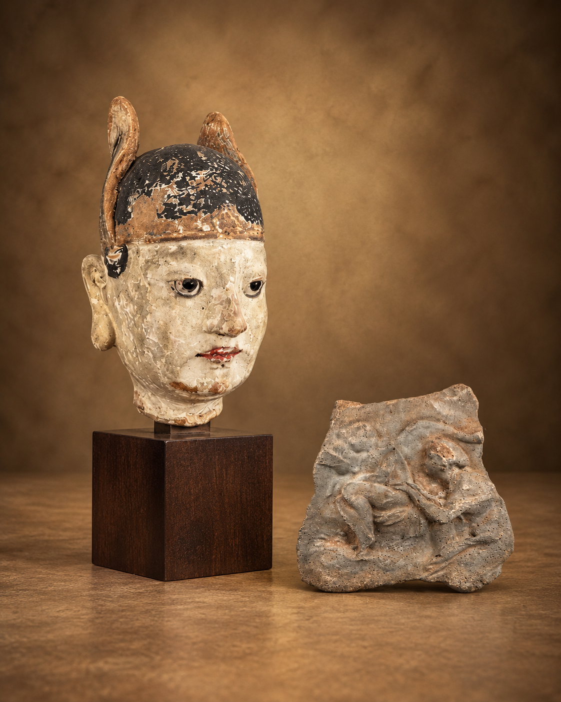 Chinese polychrome temple figure head and ancient Roman volcanic tuff relief fragment displayed in the Relic & Rarity Ancient Artifacts collection.