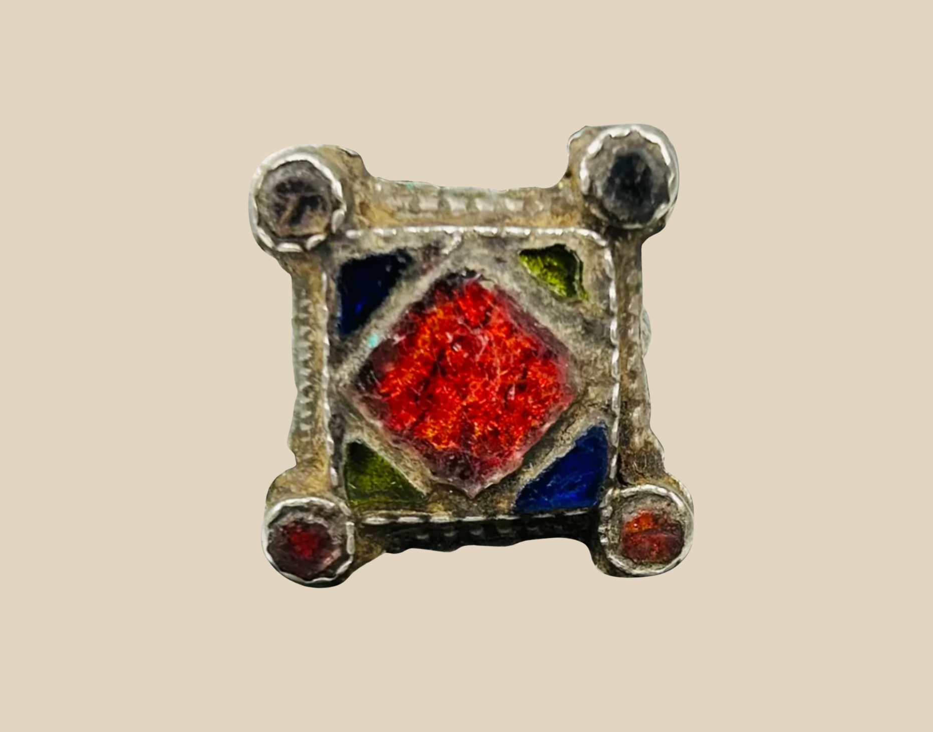 Ancient silver ring featuring a red gemstone inlay surrounded by blue and green enamel panel