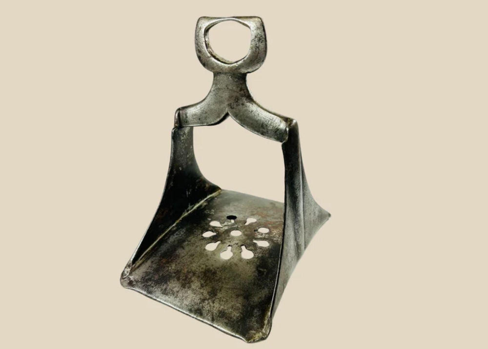 Authentic 17th-century Ottoman forged steel stirrup with triangular form, openwork floral cut-out footplate, and traces of silver damascening; historically used by elite cavalry for mounted combat and control.