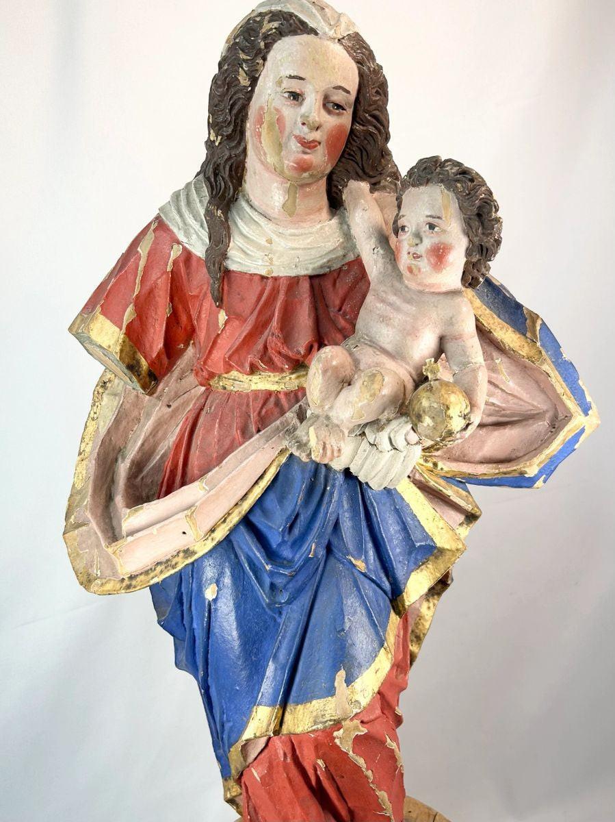 Spanish Colonial Madonna and Child statue, circa 1780–1820, hand-carved wood with original polychrome and gilding. Virgin in red and blue robes with gilt highlights holds infant Christ with golden orb. Mounted on original socle with craquelure and age wear.