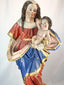Spanish Colonial Madonna and Child statue, circa 1780–1820, hand-carved wood with original polychrome and gilding. Virgin in red and blue robes with gilt highlights holds infant Christ with golden orb. Mounted on original socle with craquelure and age wear.