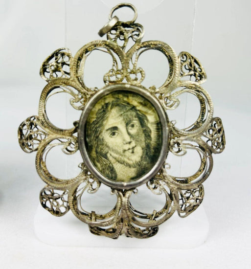 Antique 19th-century Catholic devotional pendant with ornate silver filigree frame and engraved portrait of Christ under glass, likely Italian or Spanish origin.