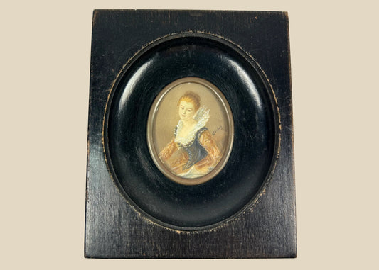 Mid–late 19th-century Continental European miniature portrait of a young woman in historicizing costume with deep blue bodice, amber sleeves, and lace ruff, watercolor/gouache on thin wafer, signed lower right, in ebonized wood frame with oval brass bezel, after Fragonard, circa 1860–1890.