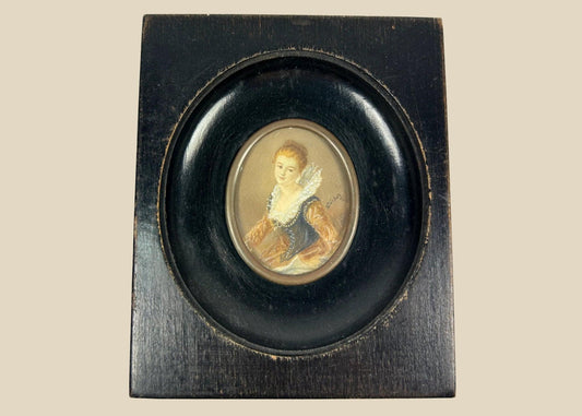 Mid–late 19th-century Continental European miniature portrait of a young woman in historicizing costume with deep blue bodice, amber sleeves, and lace ruff, watercolor/gouache on thin wafer, signed lower right, in ebonized wood frame with oval brass bezel, after Fragonard, circa 1860–1890.