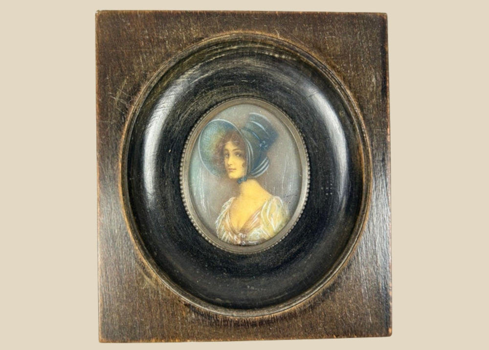 Antique 19th-century Viennese miniature portrait of a woman in blue bonnet and lace gown, painted in gouache on wafer, in original ebonized wooden frame with convex glass.
