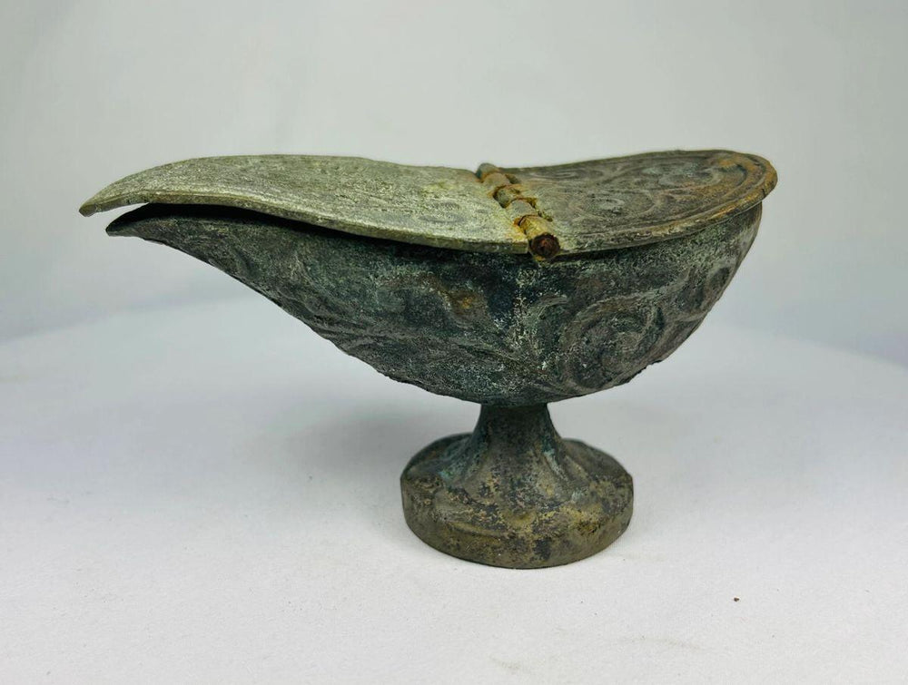 Side profile of Han Dynasty bronze oil lamp with elongated spout, engraved scroll decoration, and raised pedestal base.