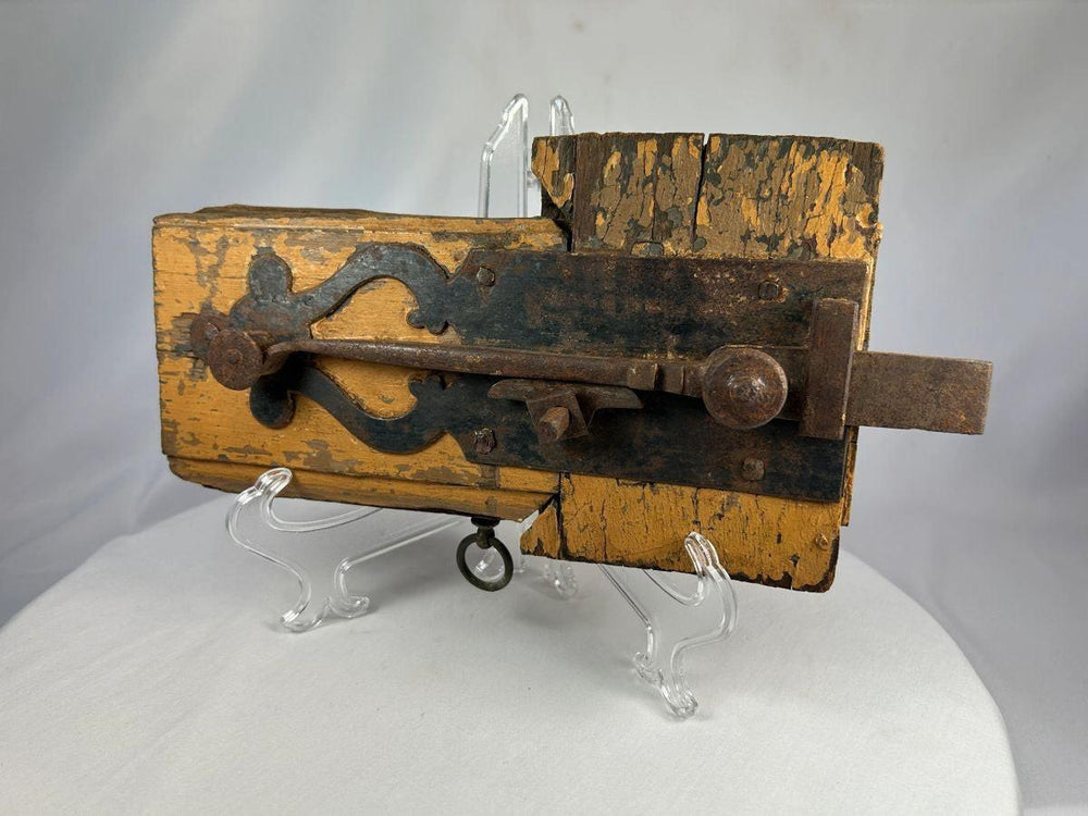 Antique colonial wooden door lock featuring wrought iron latch and aged patina