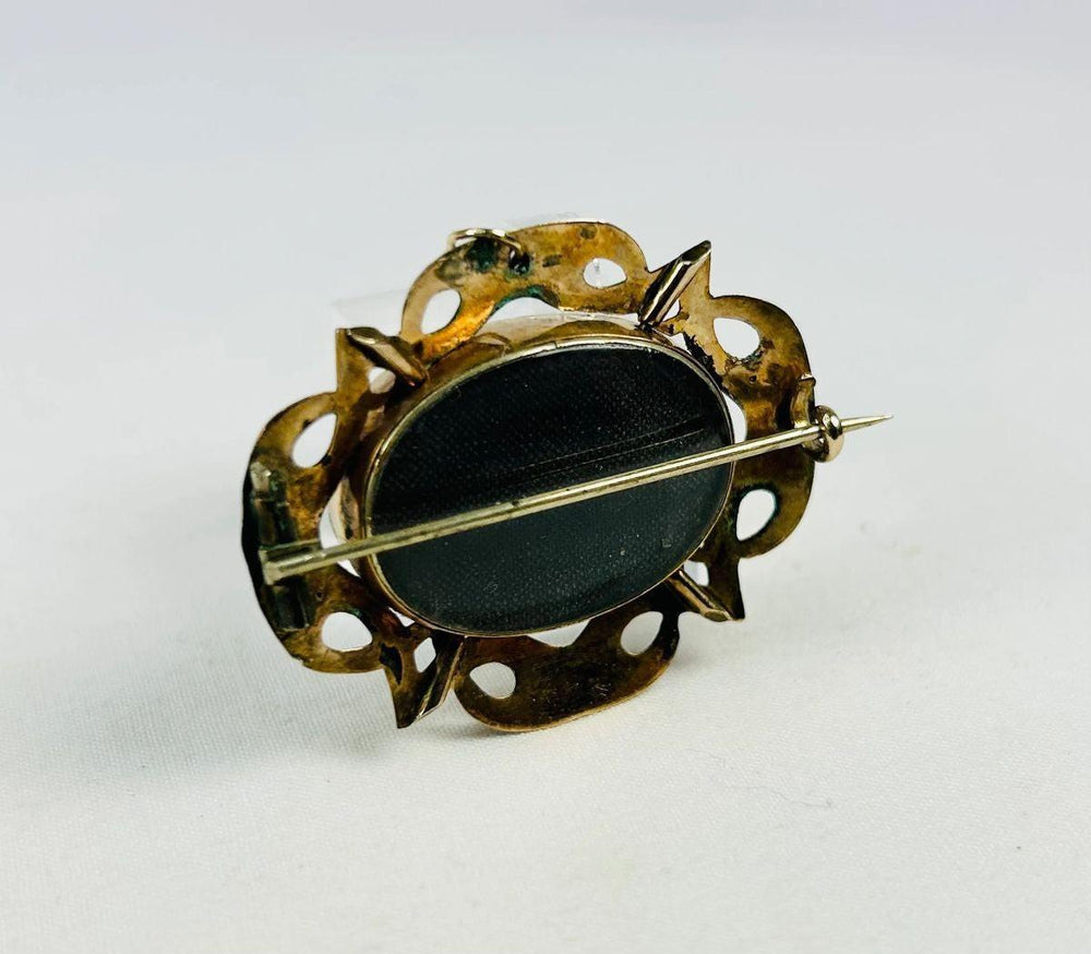 Back view of a Victorian mourning brooch showing original pin and C-clasp closure.