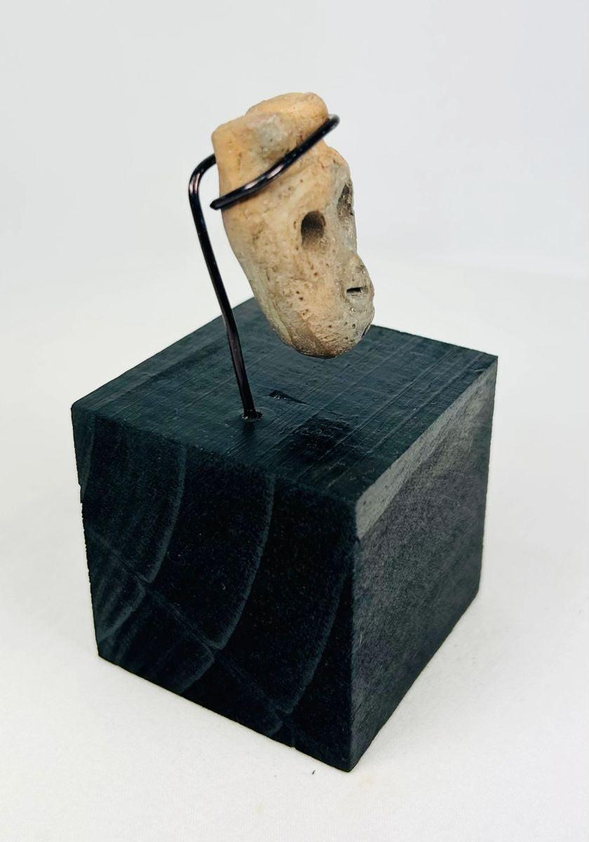 Ancient carved bone face pendant from Western Mexico showing stylized features and patina