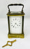 Front view of antique French carriage clock with white enamel dial and visible escapement.
