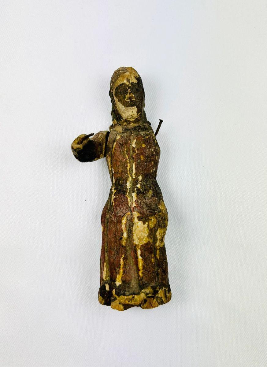 Close-up of a carved wooden santo highlighting polychrome paint remnants and hand-carved details