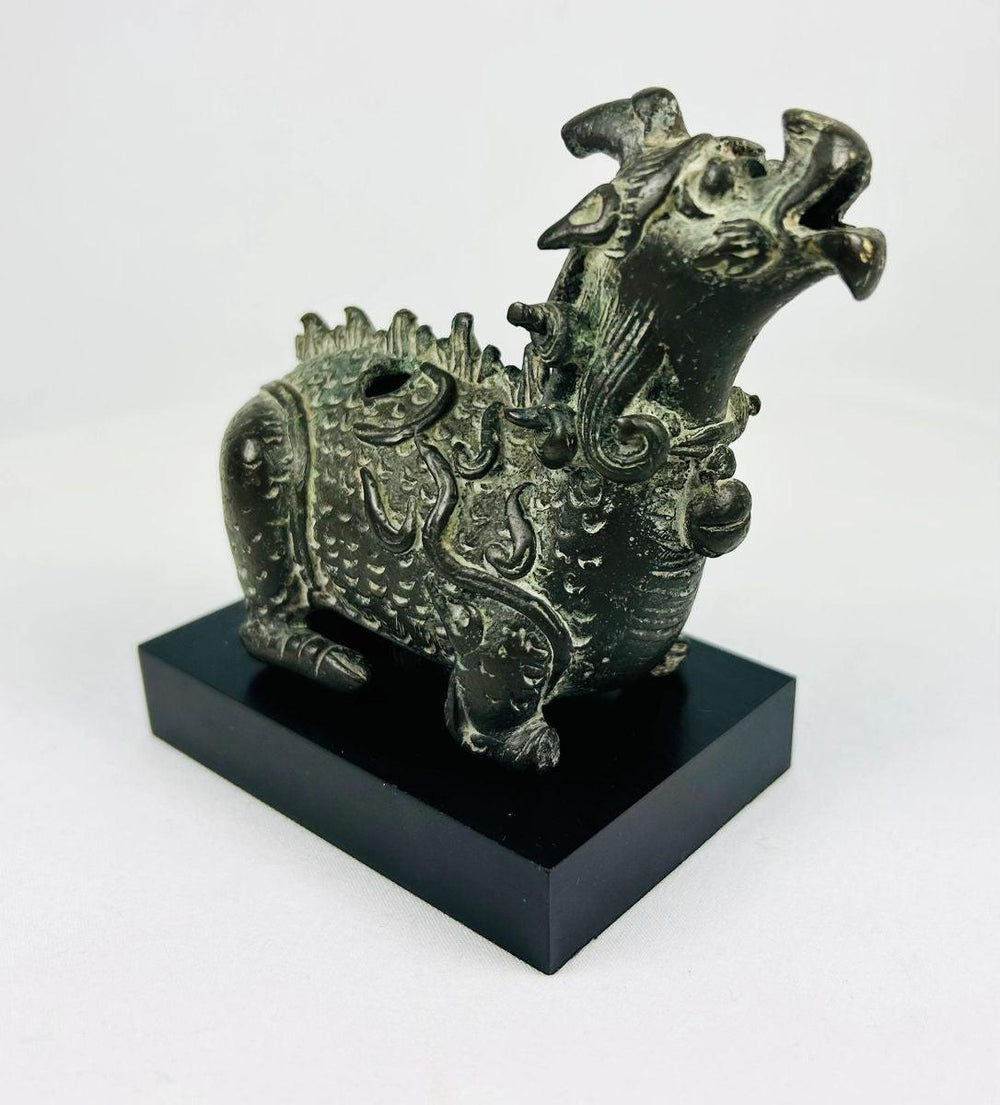 Side view of Chinese Qilin bronze censer with engraved scale pattern and curled whisker detailing, mounted on black base.