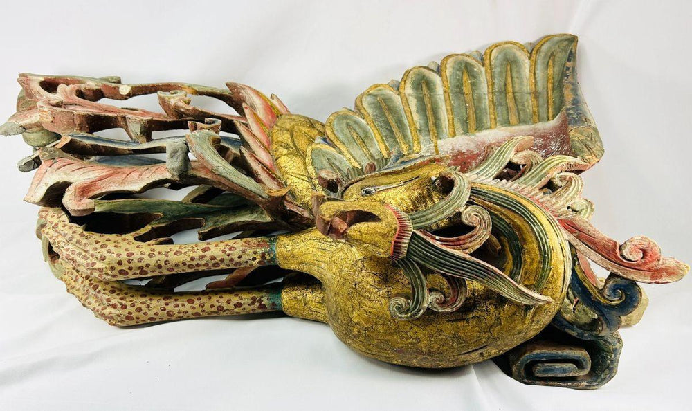 Detailed close-up of Qing Dynasty phoenix relief sculpture carved from camphor wood, with vivid red, blue, and gold gilded plumage representing the Fenghuang – Relic and Rarity.