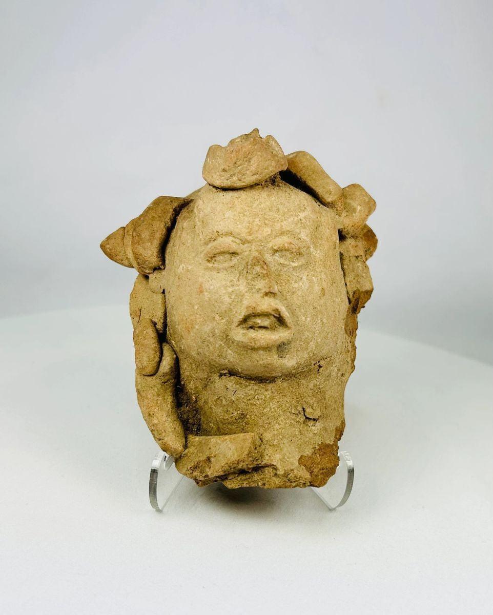 Ancient clay head from Pre-Columbian cultures with carved features and pigment traces