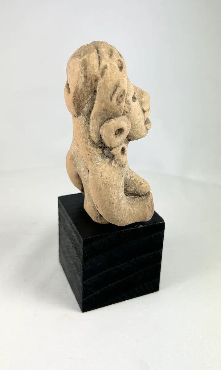 Pre-Columbian terracotta seated woman from West Mexico, featuring large ear ornaments and stylized face