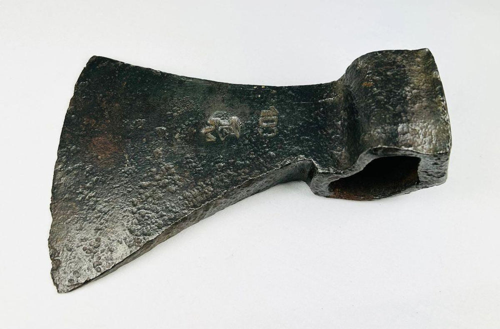 Antique European iron axe head showing maker’s mark and aged surface patina
