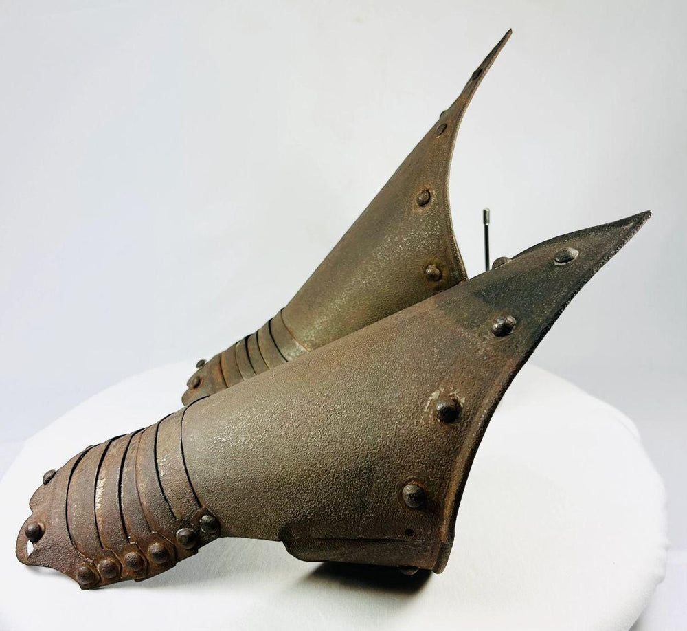 Side angle of Gothic-inspired metal gauntlets showing articulated plates and rivets.