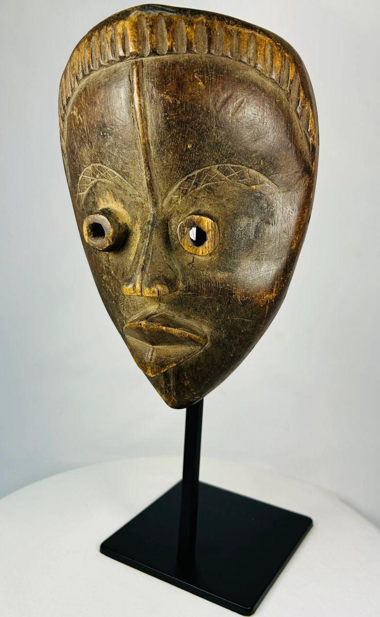 Antique Baule mask from Ivory Coast featuring almond-shaped eyes and carved coiffure