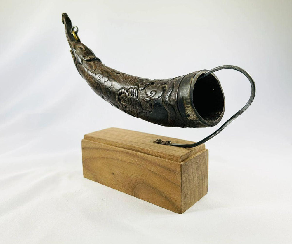 Side profile of carved Tibetan Buddhist horn with symbolic patterns.